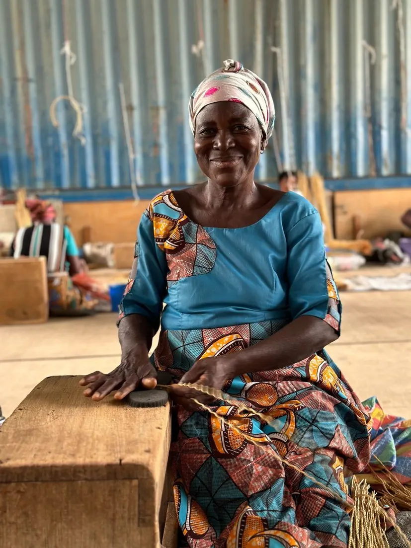 A basket maker splitting natural straw while seated at the compound