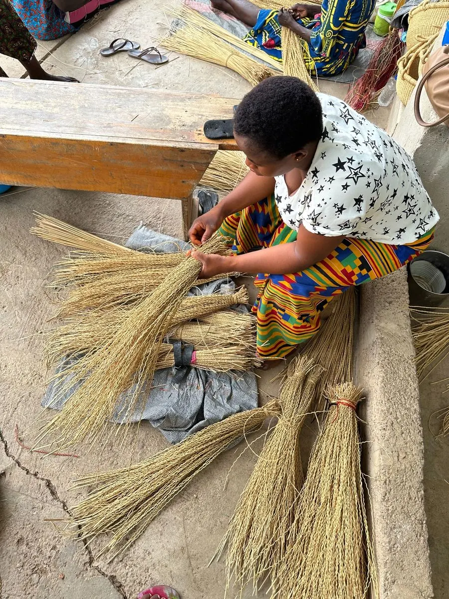 A basket maker preparing bundles of straw at the compound