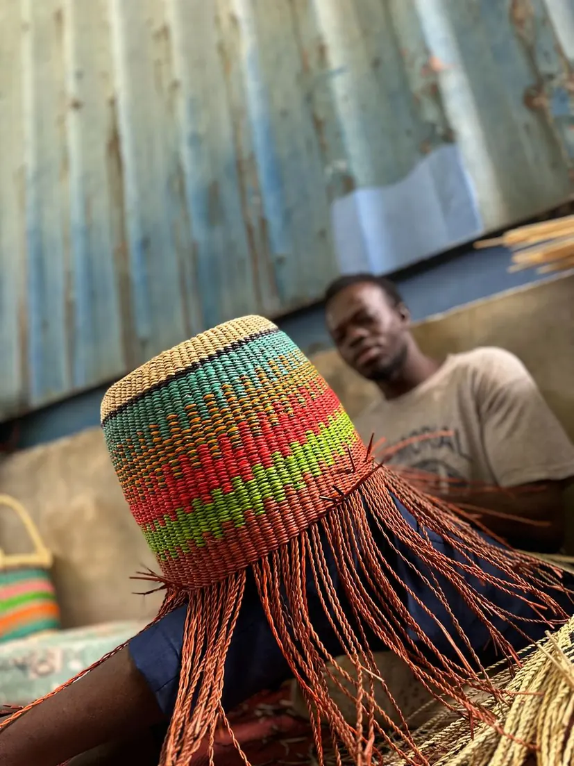 A basket maker weaving the rising sides of a colourful basket