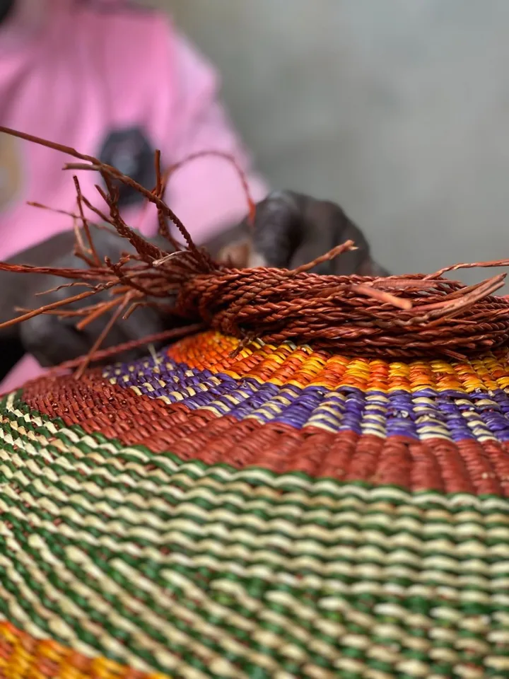 Close view of the final rows and loose strands of a colourful basket