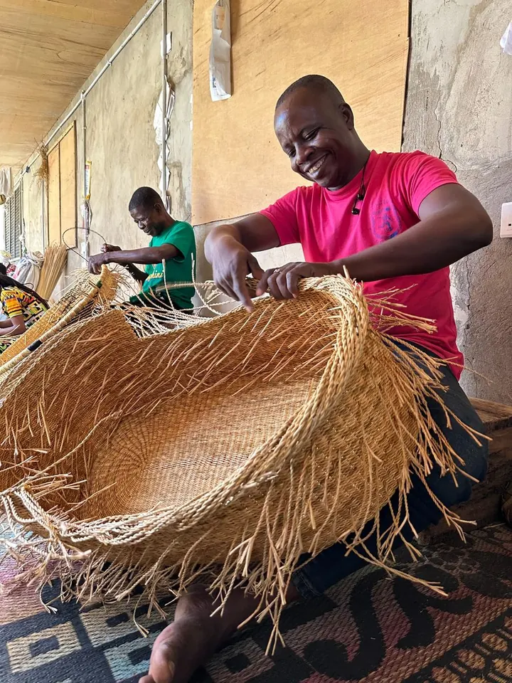 A basket maker finishing the edge of a natural straw basket