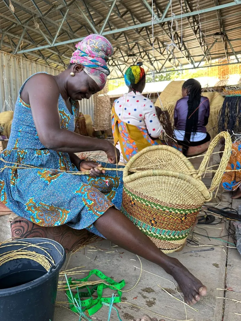 A basket maker working on the handle of a round market basket